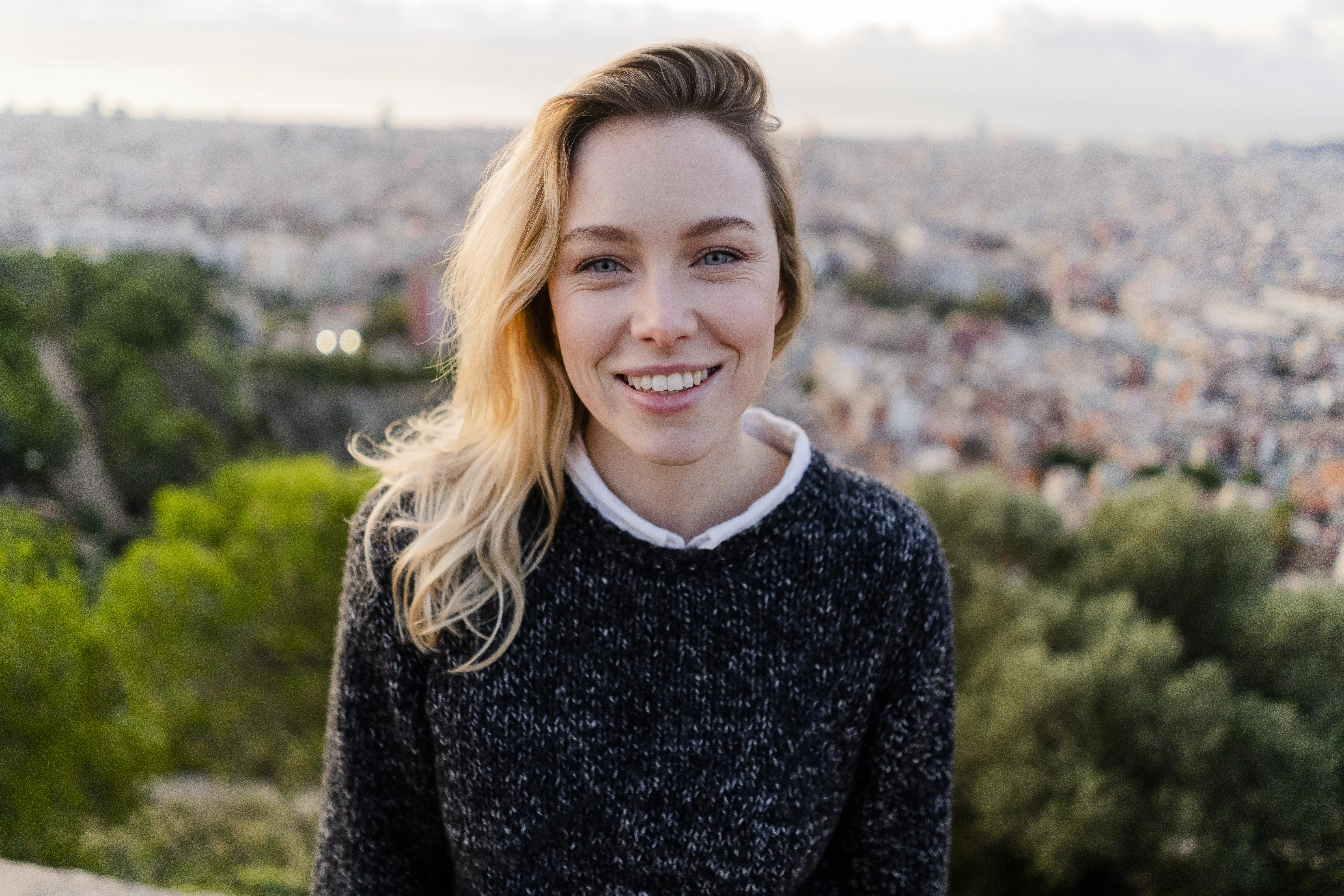 Portrait of smiling young woman at sunrise above the city, Barcelona, Spain
